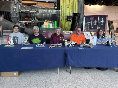 Five Wamalug participants and their creations among aircraft exhibits in a museum.